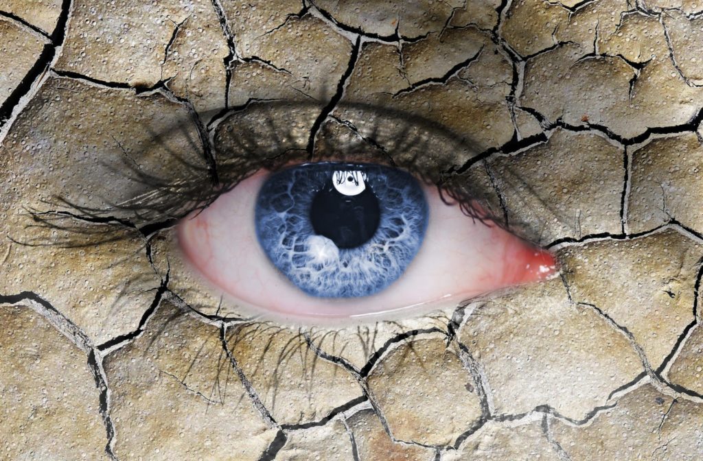 dramatic edit of a close-up shot of a woman's blue eye with the skin stylized into a cracked desert floor