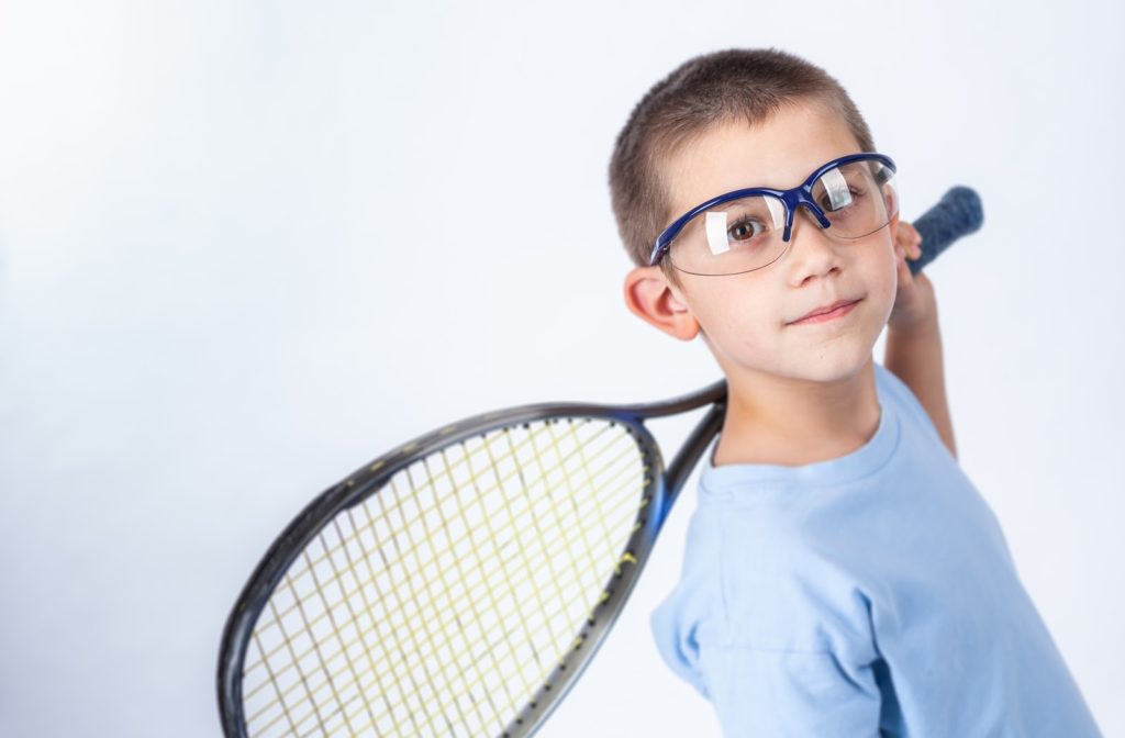 Young boy holding his squad racket and has protective eyewear on.