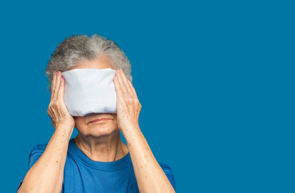 An old woman is using a warm compress on her eyes to relieve dry eyes,
