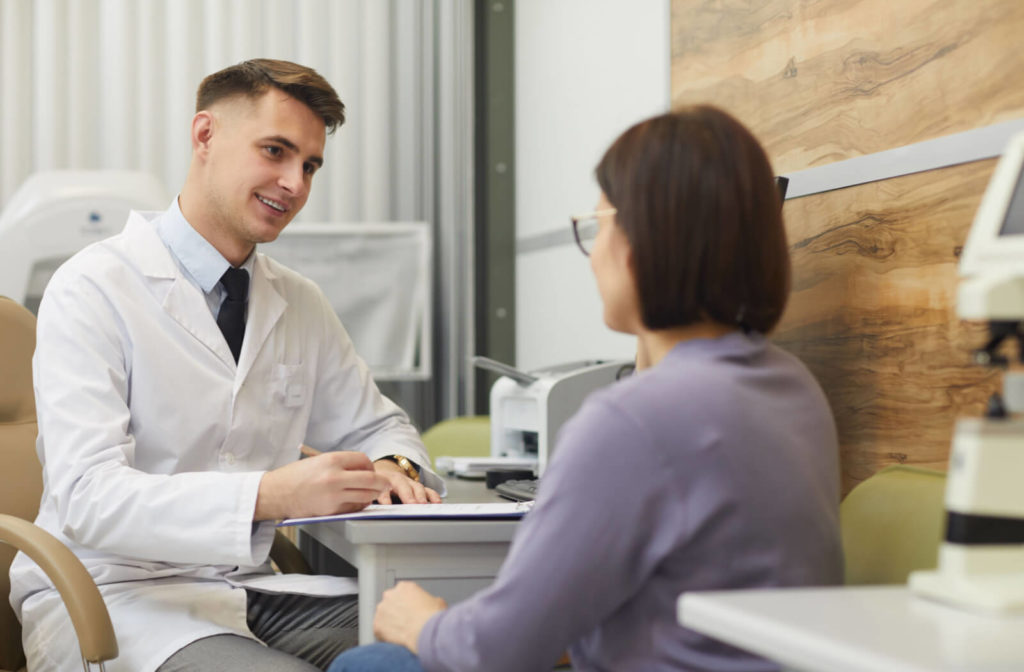 Optometrist attentively listens to his patient while jotting down some notes