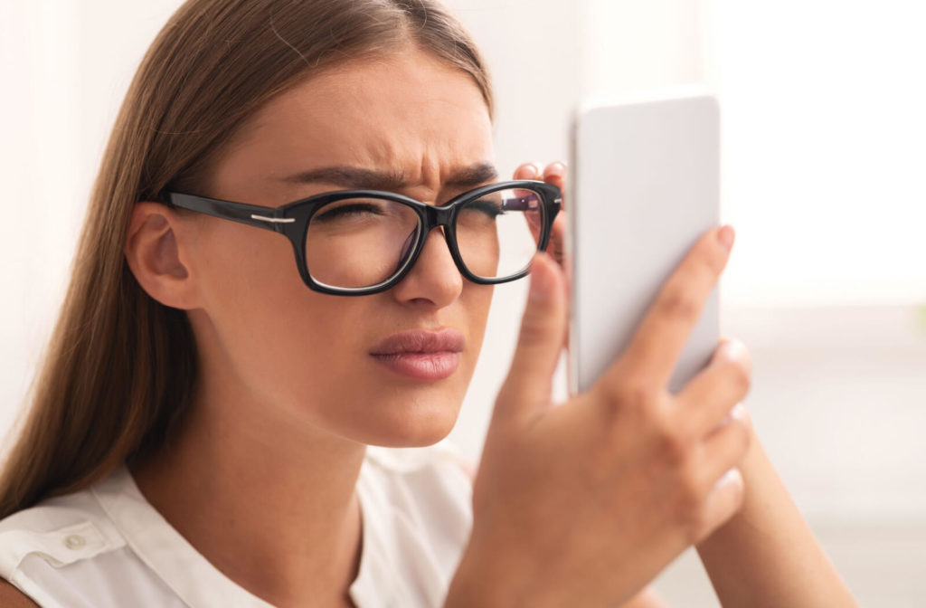 A woman holding her phone closer to her face to see its content better.