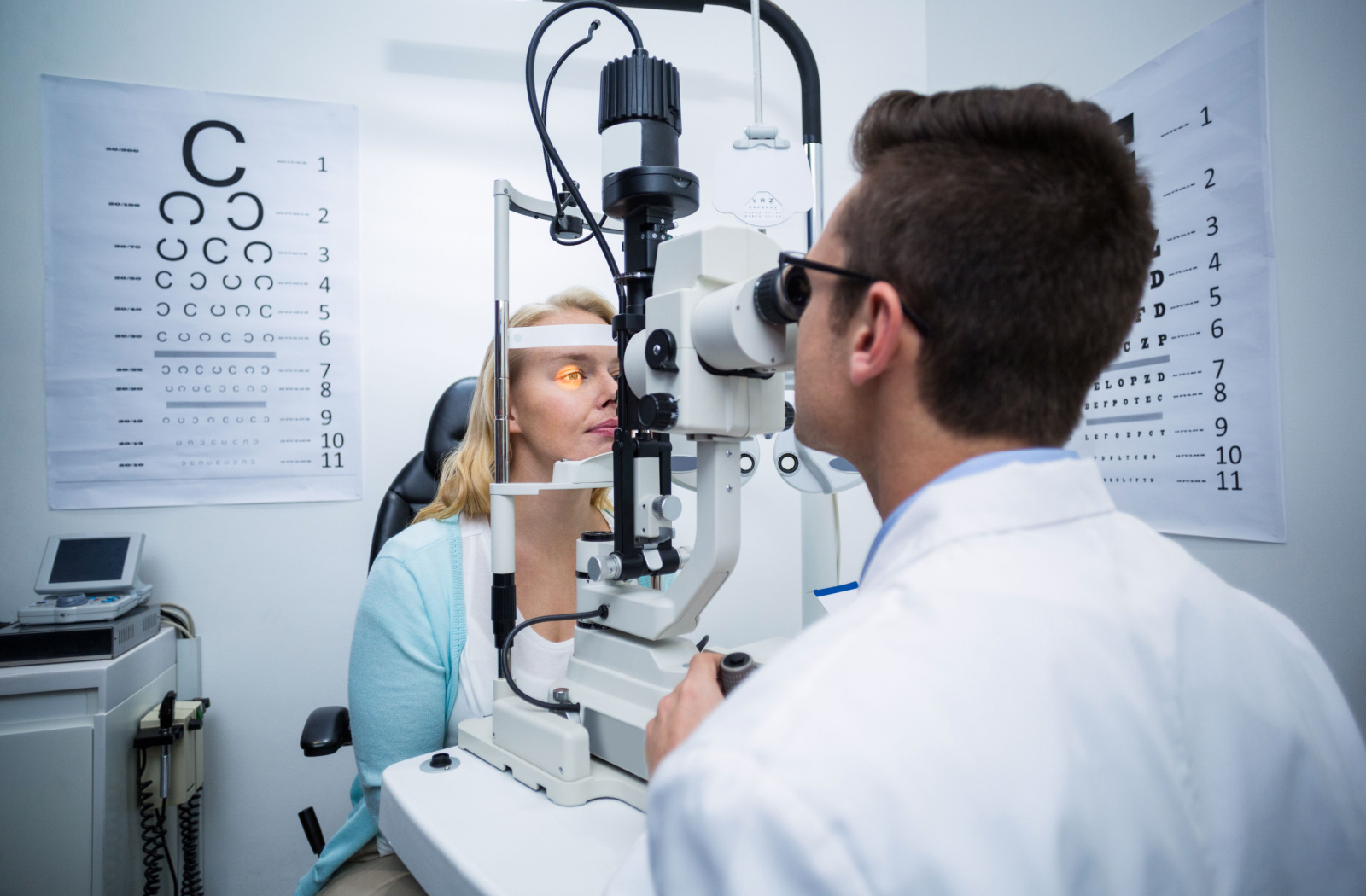 An optometrist performing a slit-lamp exam on his patient