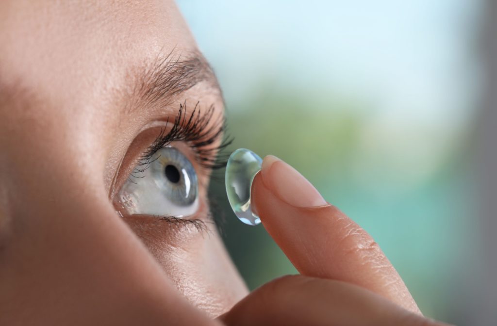 A closeup showing a young man applying her contact lens.