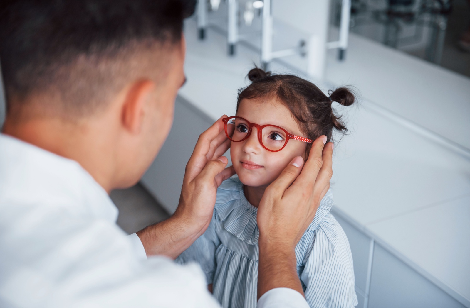 An optician fitting glasses for a toddler.