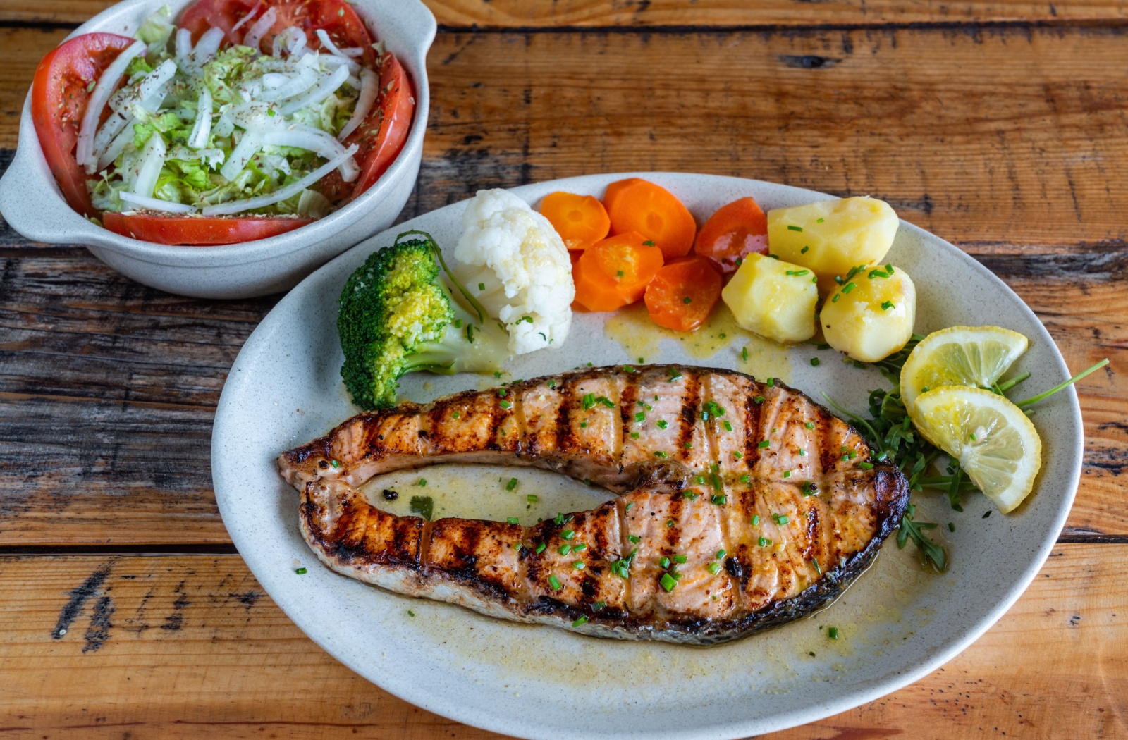 A plate full of salmon and roasted veggies with a side salad.