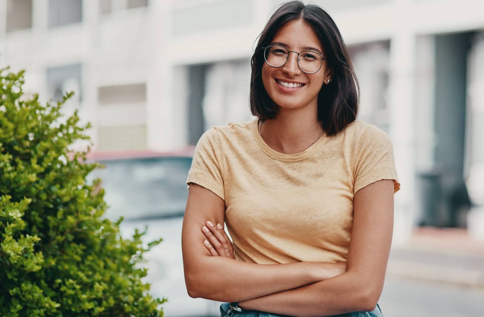 Person wearing stylish glasses smiling confidently outdoors, highlighting clear vision and self-assuredness
