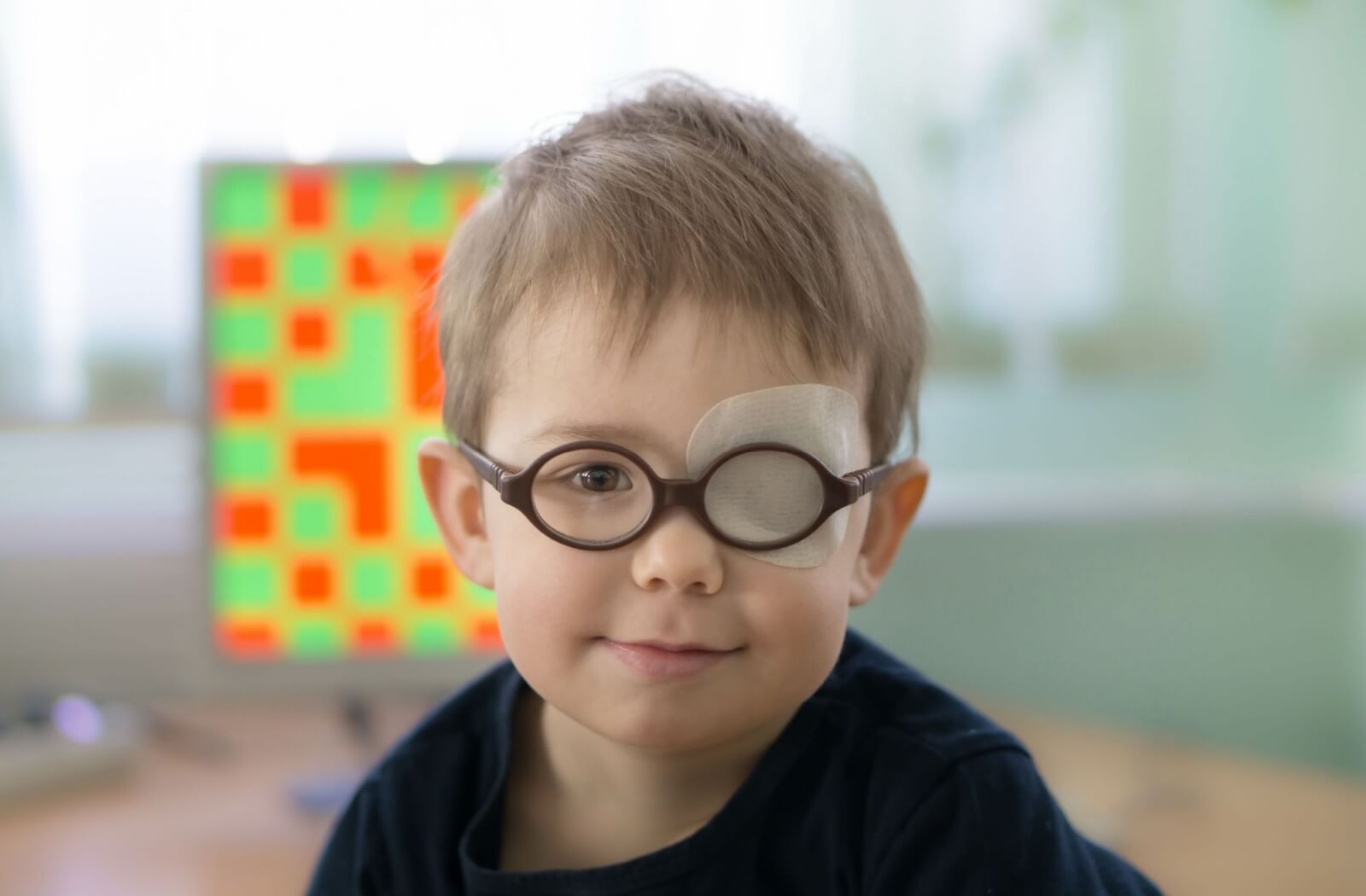 Young child wearing glasses and eye patch for amblyopia treatment.