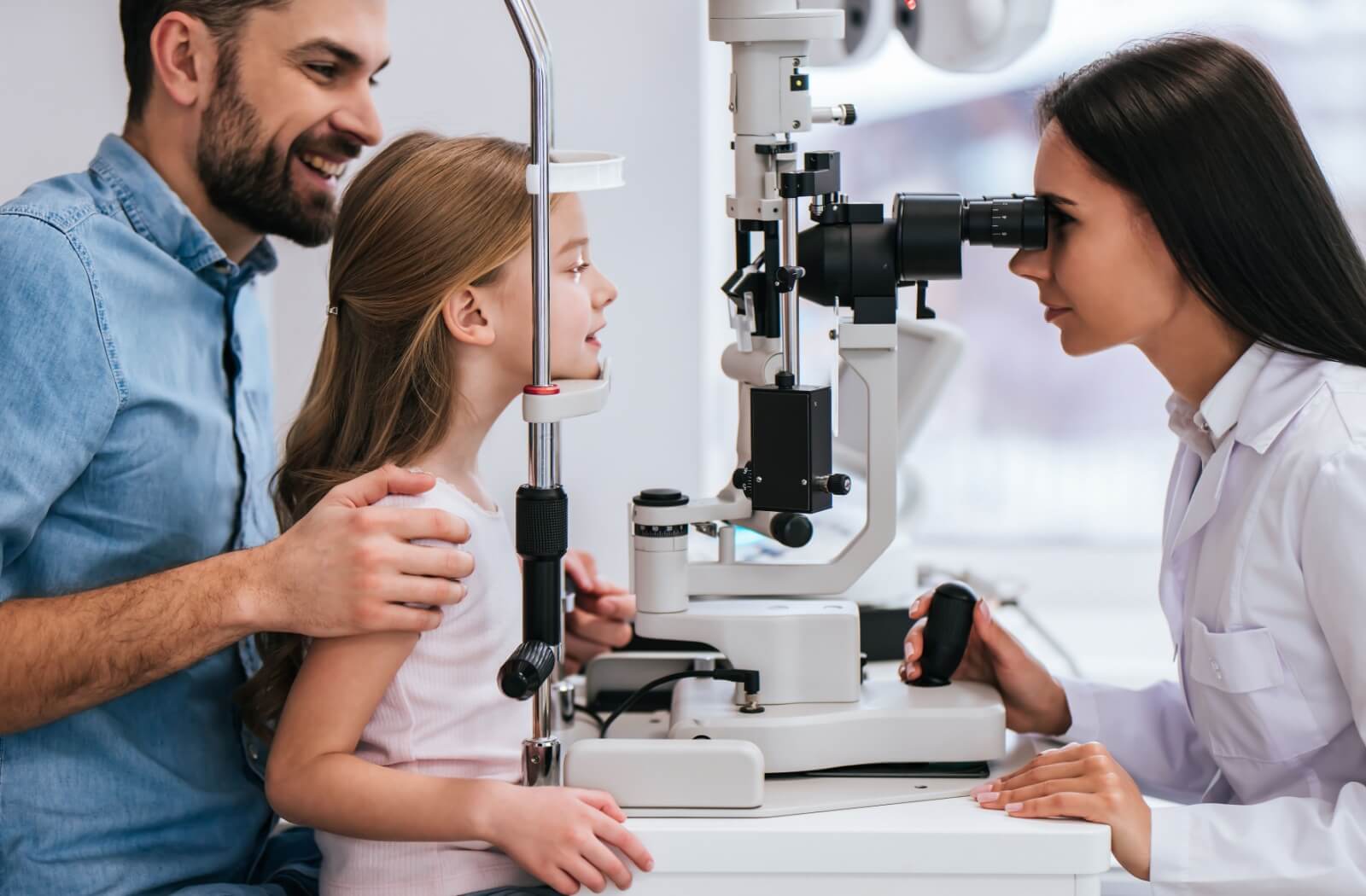An optometrist evaluates a child's eyes with a slit lamp during their annual eye exam.