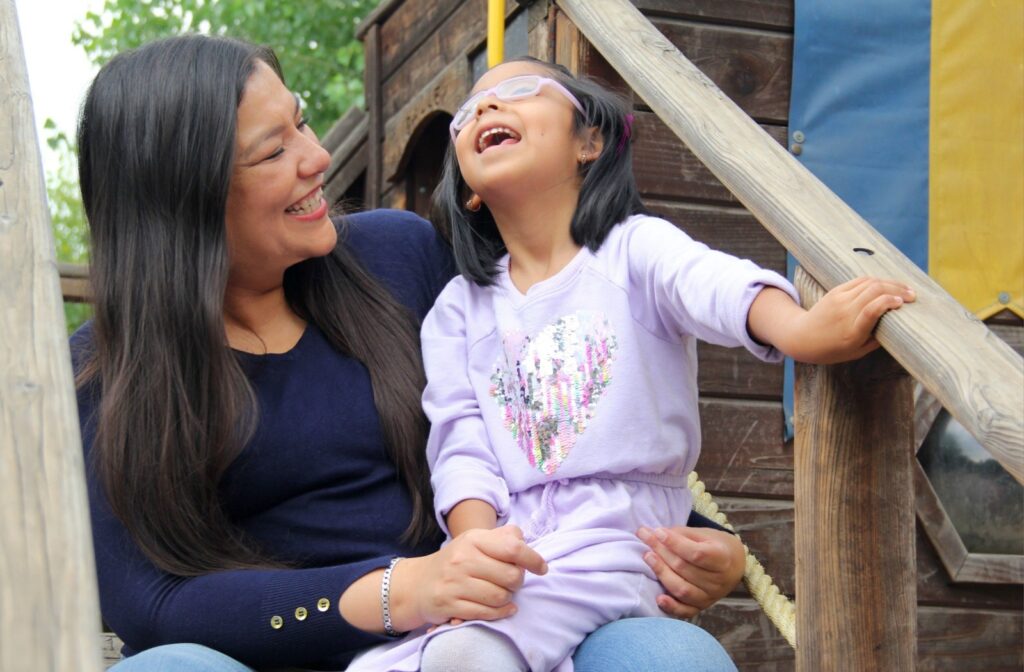 A mother and her child sitting together and smiling at a park