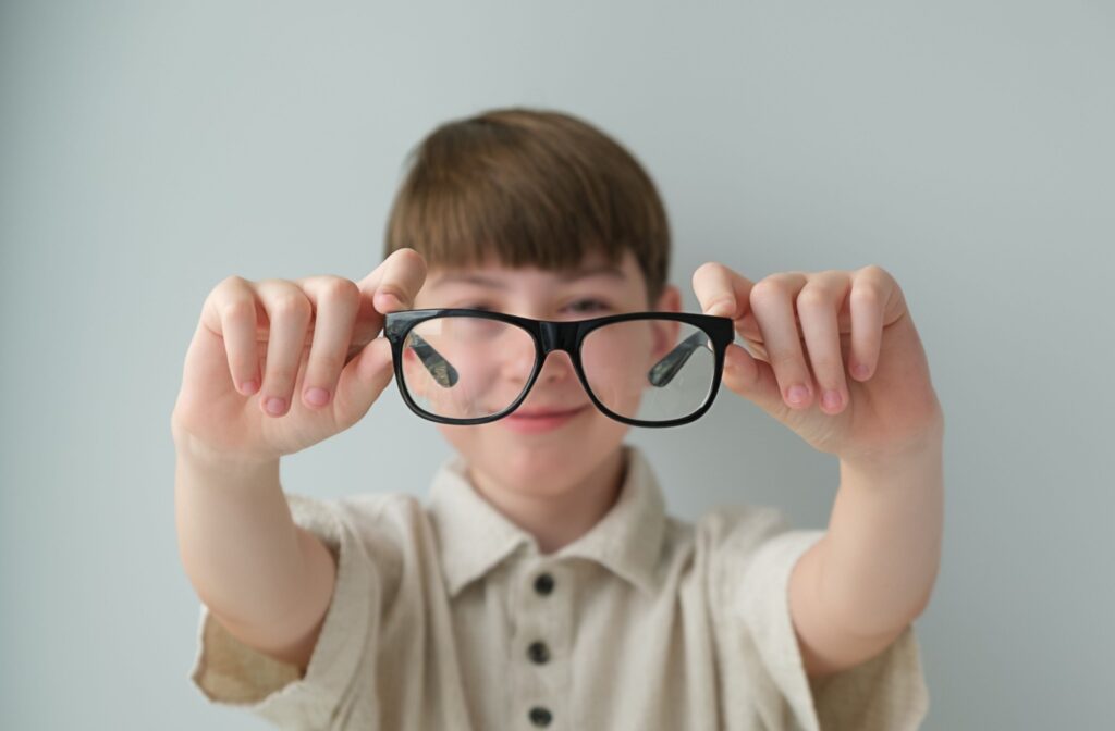 A child holding up a pair of glasses in front of their face
